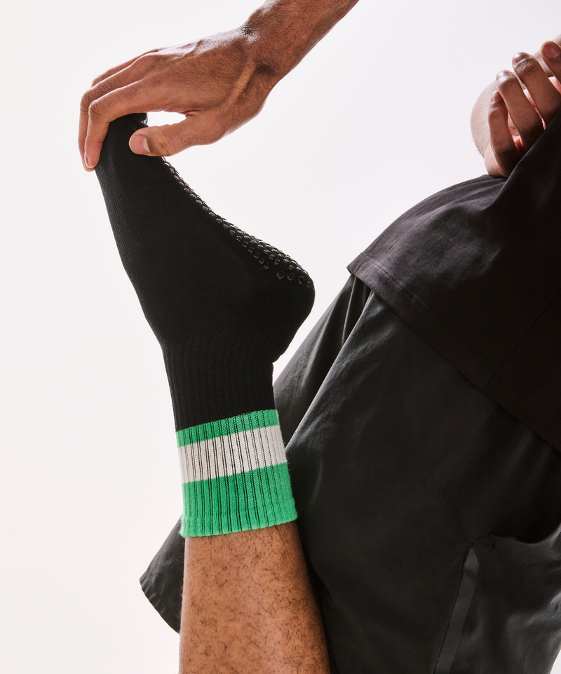 Pair of men's crew non slip grip socks with black and green stripes